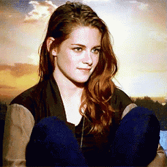 a woman with long red hair is sitting with her legs crossed in front of a cloudy sky