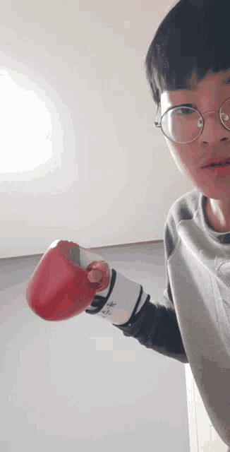 a young boy wearing glasses and boxing gloves with the letter m on the sleeve