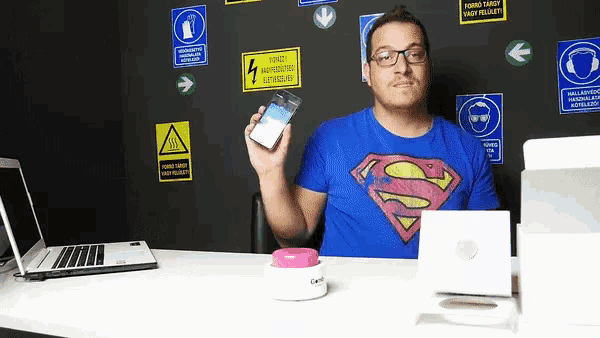 a man in a superman shirt holds a cell phone