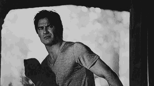 a man in a grey t-shirt is standing in a black and white photo