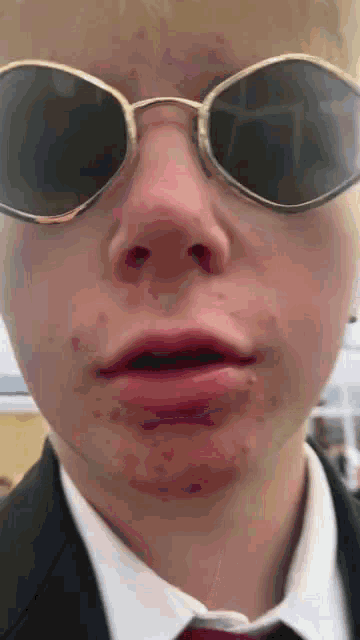a close up of a man wearing sunglasses and a suit