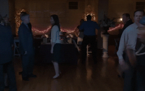 a group of people are dancing on a dance floor in a dark room