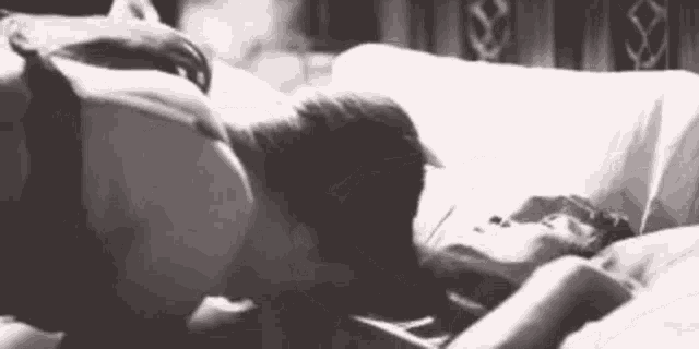 a man and a woman are laying on a bed and kissing .