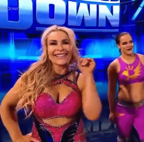 two women are standing next to each other on a stage in front of a sign that says `` down '' .