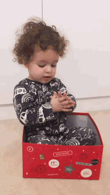 a little boy is sitting in a red box that says 14th november on it