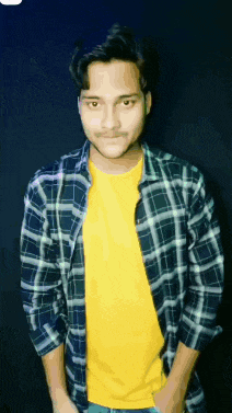 a young man wearing a plaid shirt and a yellow shirt .