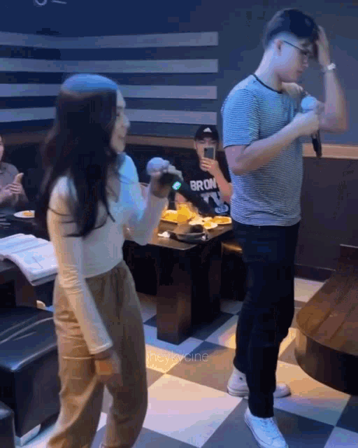 a man wearing a bronx shirt is standing next to a woman singing into a microphone