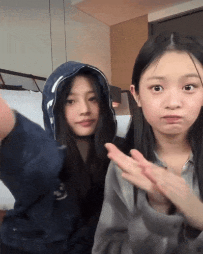 two girls are posing for a picture and one is wearing a blue hoodie with the letter p on it