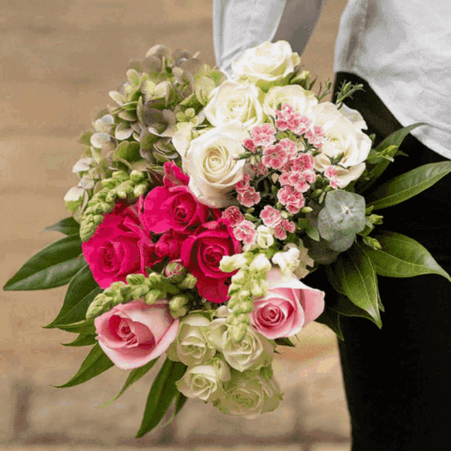 a woman is holding a bouquet of pink and white roses