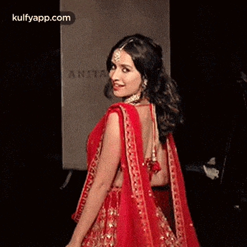 a woman in a red dress is walking down the runway .