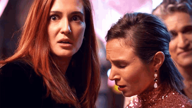two women are standing next to each other with one wearing a pink dress