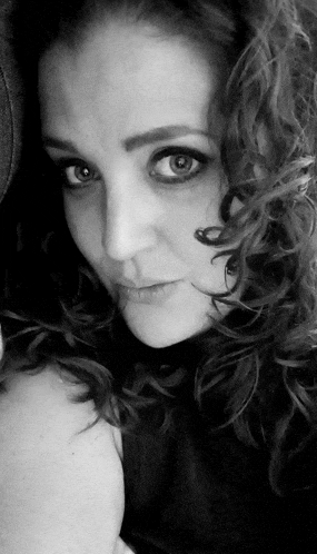a black and white photo of a woman with curly hair looking at the camera