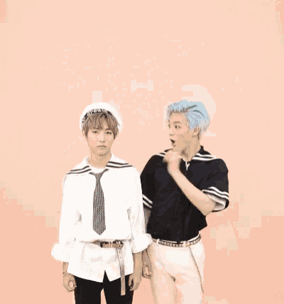 a couple of men are dancing in front of a pink wall with music notes .