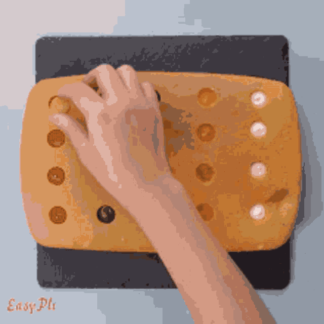 a person 's hand is reaching for a piece of food on a cutting board that says easy pli on the bottom