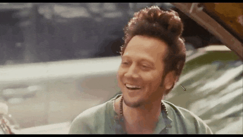 a man with a bun on his head is laughing in a car .