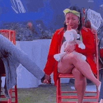 a woman is sitting on a chair holding a teddy bear .