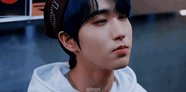 a close up of a person wearing a beanie and a white hoodie