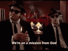 two men in suits and hats are smoking a cigarette and saying we 're on a mission from god