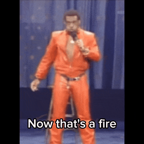 a man in an orange suit is standing on a stool holding a microphone and says now that 's a fire
