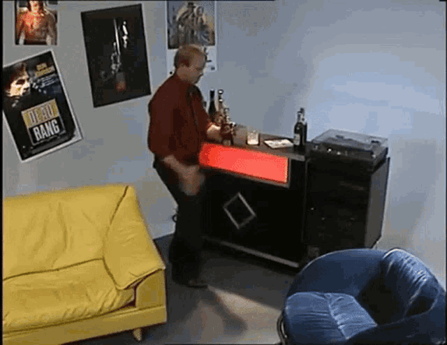 a man is standing at a bar with a dead bang poster on the wall behind him