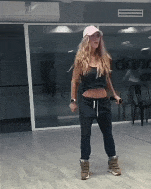 a woman in a pink hat is dancing in front of a dance studio