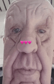 a close up of an older man 's face with three pink hearts on his nose