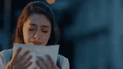 a woman is covering her face with a piece of paper .