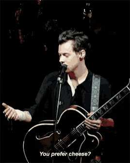 a man singing into a microphone while holding a guitar and the words " you prefer cheese " below him