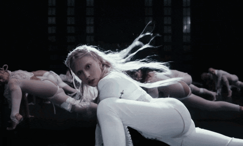 a woman in a white outfit is kneeling down with her legs crossed