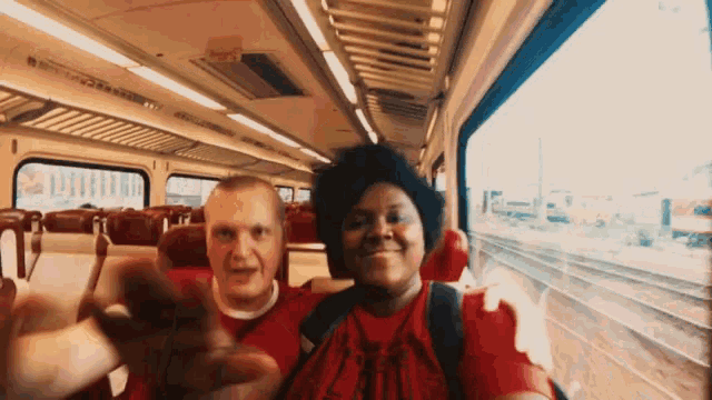 a man and a woman are sitting on a train waving