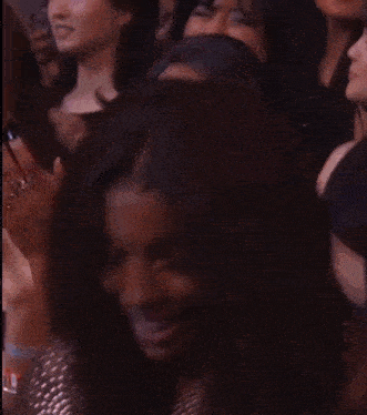 a woman stands in front of a crowd of people applauding her