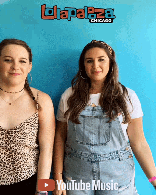 two women standing in front of a blue wall with a youtube music logo