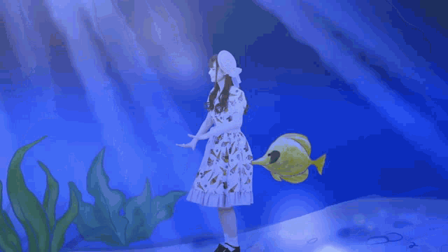 a girl in a white dress is holding a fish in her hands