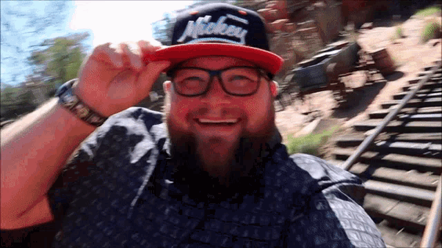 a man wearing a mickey hat and glasses smiles for the camera