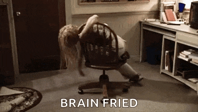 a woman is laying on an office chair in a room with the words `` brain fried '' written on the floor .