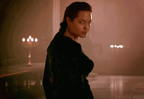 a woman in a black shirt is standing in a dark room with candles .