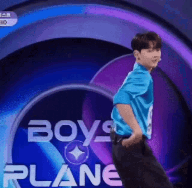 a man in a blue shirt is dancing on a stage in front of a sign that says `` boys plane '' .