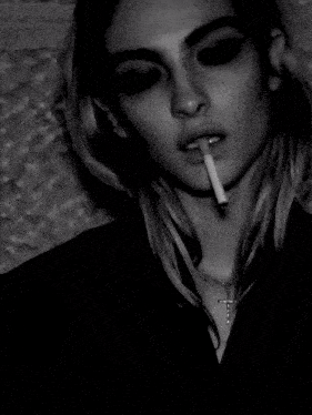 a woman smoking a cigarette with a cross necklace
