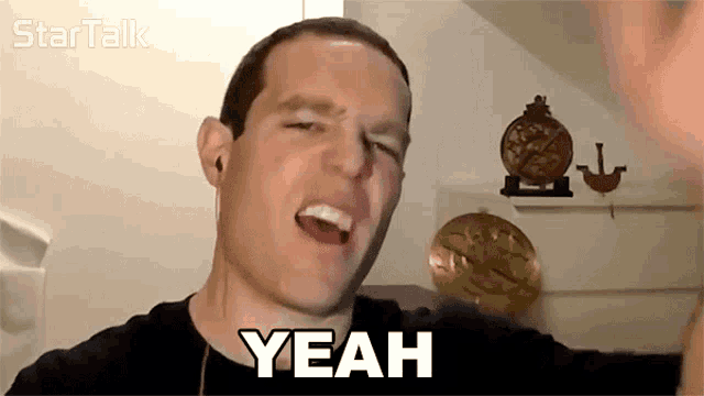 a man says yeah in front of a clock on a wall