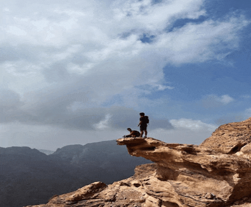 a man with a backpack stands on top of a rocky mountain