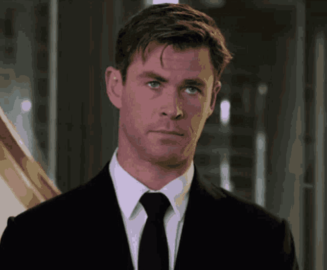 a close up of a man in a suit and tie looking at the camera