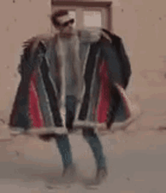 a man wearing sunglasses and a blanket is standing in front of a window holding a blanket .