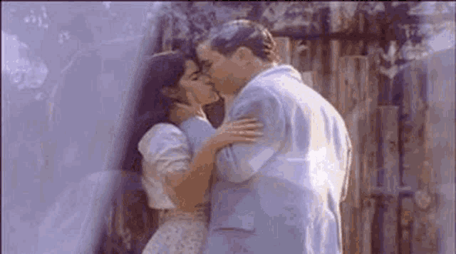 a man and a woman are kissing in front of a wooden wall .