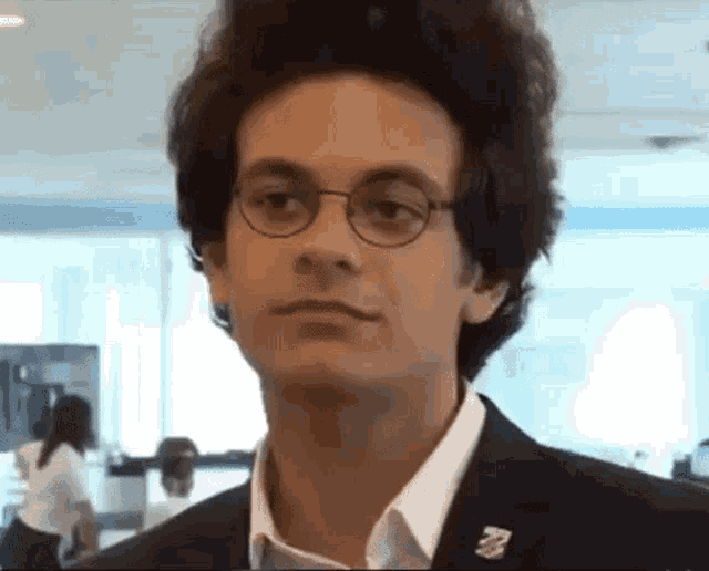 a young man wearing glasses and a pin that says ' a ' on it