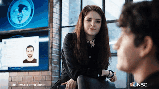 a woman sits next to a man in front of a screen that says " organized crime "