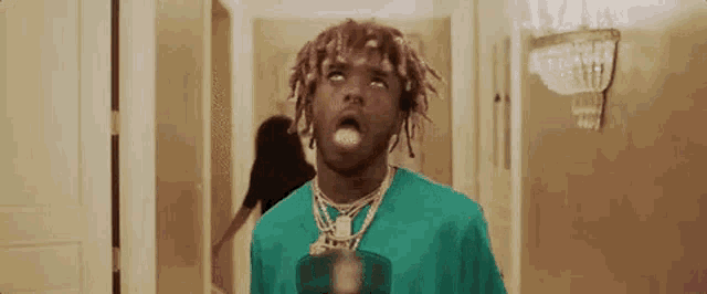 a man with dreadlocks is standing in a hallway with his mouth open and a woman behind him .