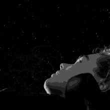 a black and white photo of a man smoking a hookah under a starry sky .