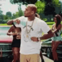 a man in a white shirt and tan shorts is standing in front of a red car .