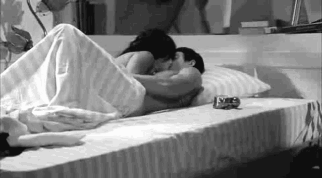 a man and a woman are kissing on a bed .