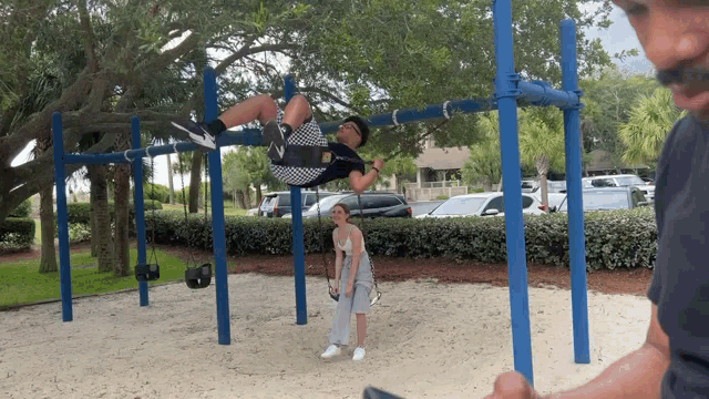 a man is hanging upside down on a swing set